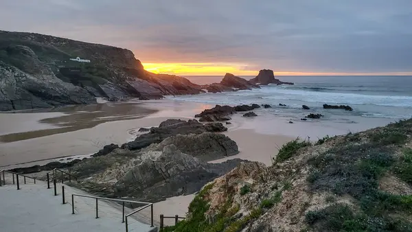 Günbatımı Zambujeira Do Mar Plajı, Alentejo, Portekiz. Portekiz Yürüyüşü Rota Vicentina Balıkçı Yolu boyunca Alentejo Kıyısı boyunca Vahşi ve Engebeli Sahillere Dar Sahil Yolları.