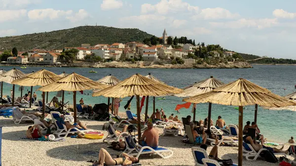 Primosten Hırvatistan 30 Temmuz 2024, Hırvatistan 'ın Akdeniz kıyısındaki Idyllic Sahili, Hırvatistan' ın Ortaçağ Primosten Kenti. Yaz Tatili Seyahat Mekanı Turistler güneşleniyor ve Mala Raduca Sahili 'nin tadını çıkarıyor.