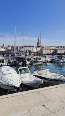 Güneşli bir yaz gününde Krk Adası 'ndaki tekne ve yatlarla dolu limanın manzarası. Sakin Deniz, Mavi Gök ve Kıyı Büyüsü Rahat Bir Akdeniz Atmosferi Oluşturur.