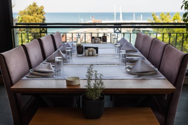 Liman kenarında deniz kenarı ve arka planda yatları olan bir lokantada akşam yemeği karamsar ve romantik.