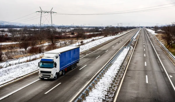 Highway transportation with large Lorry truck passing trucks in a snowy winter landscape