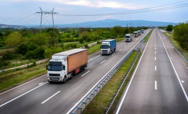 Otoyolda konteynırları olan uzun kamyon konvoyu, ilkbaharda kargo taşımacılığı konsepti - nakliye hizmeti