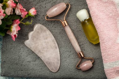 Jade Roller and Gua Sha for beauty facial massage therapy with towel. Flat lay on marble background