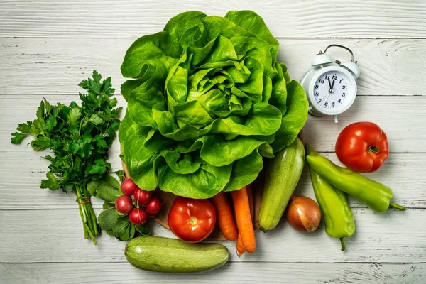 Diet time. Food clock. Healthy food concept with vegetables on wooden table