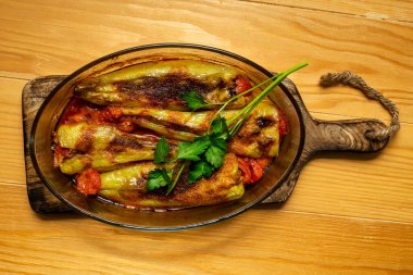 Doldurulmuş biber, oval bir cam kapta domates sosuyla pişirilmiş.