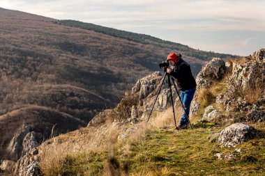 Fotoğrafçı, dağlardaki bir tripoda dijital kamerayla fotoğraf çekiyor. Seyahat ve aktif yaşam tarzı kavramı