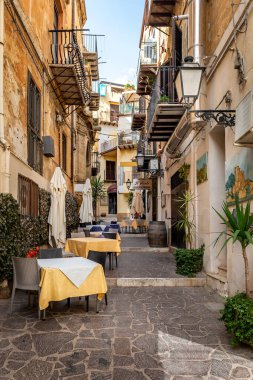 Agrigento, Sicilya, İtalya - 19 Mayıs 2023: Agrigento, Sicilya 'da renkli seramik süslemeleri olan eski tarihi binalar, dar sokaklar ve restoran masaları