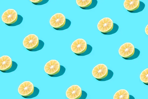 Trendy Summer food pattern made with yellow lemon slice on bright light blue background. Minimal summer concept.