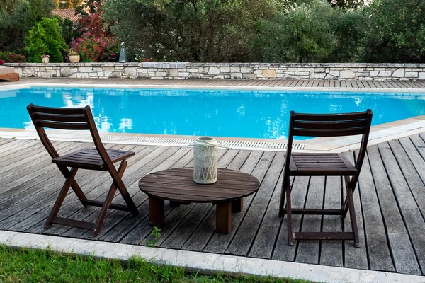 Swimming pool and chairs for relaxing in summer. Swimming pool in the nature among greenery.