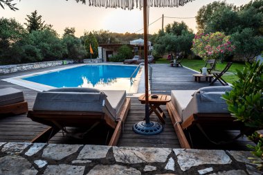 Yazın dinlenmek için havuz ve yataklar. Doğada yeşillikler arasında yüzme havuzu.