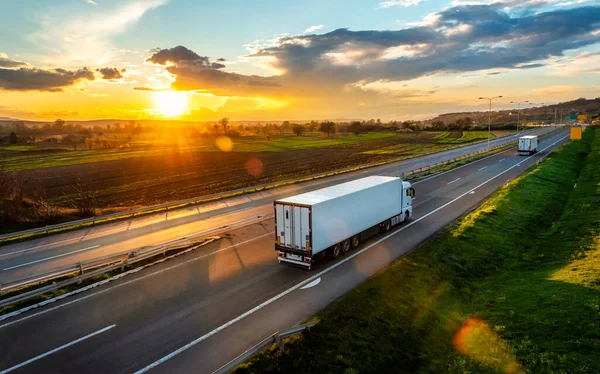 美しい夕日の田舎を通る高速道路の道路上の大型輸送トラック ロイヤリティフリーのストック画像