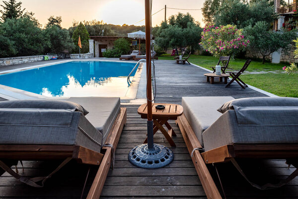 Плавательный бассейн и кровати для отдыха летом. Бассейн на природе среди зелени.