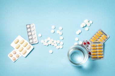 İlaç şişesinden dökülen beyaz haplarla dolu bir bardak su. Sağlık ve aşırı doz kavramı