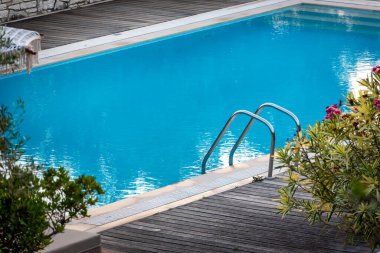 Yazın dinlenmek için havuz ve yataklar. Doğada yeşillikler arasında yüzme havuzu.