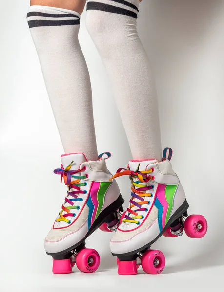 Portrait of woman legs wearing four-wheeled roller blades with colorfull laces on white background