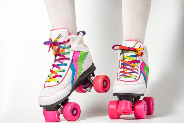 Portrait of woman legs wearing four-wheeled roller blades with colorfull laces on white background