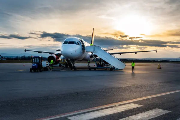 stock image Airplane at sunset - back lit. Airplane being charged and receiving cargo at the airport