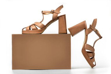 Beyaz arka planda açık kahverengi süet kadın sandaletinin stüdyo fotoğrafı.