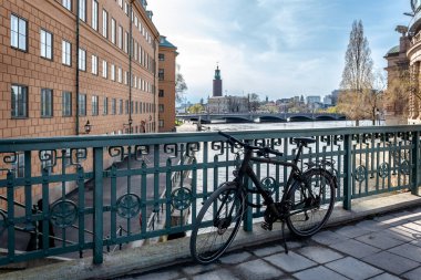 Stallbron Köprüsü 'nden Stockholm Belediyesi' nin ve Stream 'in şatosunun manzarası. Köprü parmaklıklarına kenetlenmiş bir bisikletle.