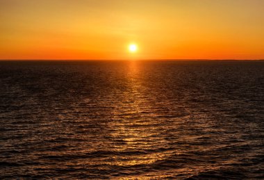 Gün batımında Baltık Denizi. Parlayan altın güneşli berrak gökyüzü, suda yansımalar. Güneş batıyor. Destansı deniz manzarası. Soyut doğal desen, doku, arkaplan, konsept resim