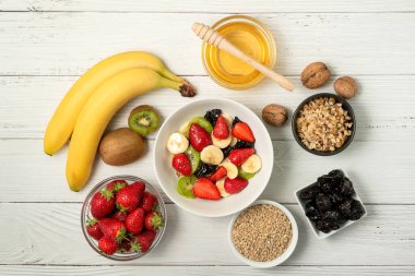 Sağlıklı kahvaltı. Sırılsıklam organik arpa, çilek, ceviz, kivi, muz, kuru üzüm, kuru erik ve bal.