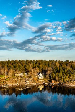 Stockholm 'ün dışındaki İsveç takımadalarında küçük cennet limanı. Sonbahar akşamı güneş lekesi ile aydınlanan güzel bir yansıması var..