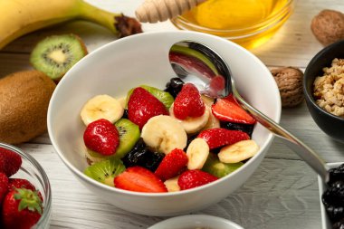 Sağlıklı kahvaltı. Sırılsıklam organik arpa, çilek, ceviz, kivi, muz, kuru üzüm, kuru erik ve bal.