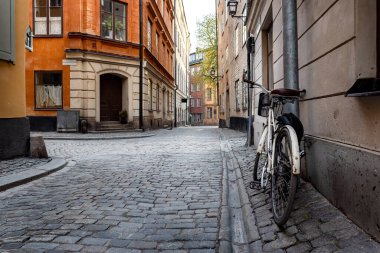 Stockholm 'ün en eski mahallesi olan Gamla Stan' deki İsveç kaldırım taşı caddesi. Park halindeki bisikletler renkli alçı binalara yaslanıyor.