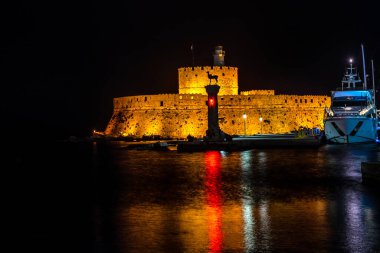Aziz Niklas Kalesi ve gece yarısı Yunanistan 'ın Rodos şehrinde aydınlatılmış bir deniz feneri.