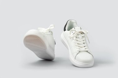 Gri arka planda izole edilmiş beyaz deri ayakkabılar. Şık, şık spor ayakkabılar. Kırpma yolu dahil