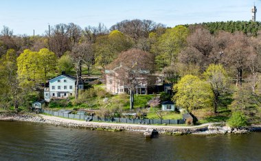 Baltık Denizi 'ndeki Stockholm Takımadaları' nın Rocky sahili. Güneşli bahar akşamları geleneksel evleri var..