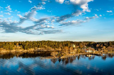 Stockholm 'ün dışındaki İsveç takımadalarında küçük cennet limanı. Sonbahar akşamı güneş lekesi ile aydınlanan güzel bir yansıması var..