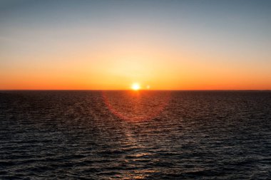 Gün batımında Baltık Denizi. Parlayan altın güneşli berrak gökyüzü, suda yansımalar. Güneş batıyor. Destansı deniz manzarası. Soyut doğal desen, doku, arkaplan, konsept resim