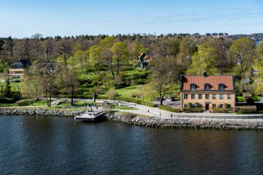 Small idyllic port in the Swedish archipelago outside of Stockholm with beautiful reflection lighted with sunspot at autumn evening. clipart