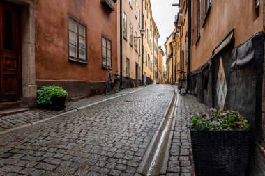 Stockholm 'ün en eski mahallesi olan Gamla Stan' deki İsveç kaldırım taşı caddesi. Park halindeki bisikletler renkli alçı binalara yaslanıyor.