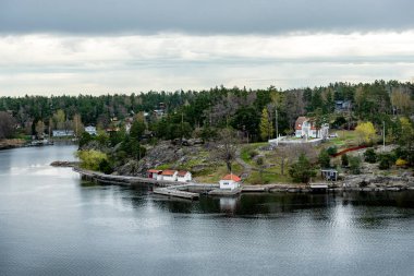 Stockholm 'ün dışındaki İsveç takımadalarında küçük cennet limanı. Sonbahar akşamı güneş lekesi ile aydınlanan güzel bir yansıması var..