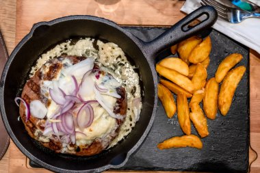 Soğan Burger. Kızartma tavasında yağda kızartılmış et köftesi ve üç çeşit soğan, yakın çekim.