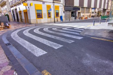 Valencia caddesinde eğri bir zebra yaya geçidi, şehir tasarımı ve güvenliğini vurguluyor.
