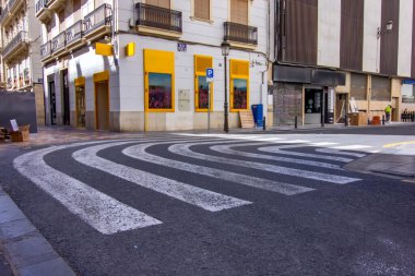 Valencia caddesinde eğri bir zebra yaya geçidi, şehir tasarımı ve güvenliğini vurguluyor.