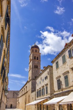 Hırvatistan 'ın Dubrovnik kentindeki taş binaların üzerinde yükselen ikonik çan kulesinin parlak bir Akdeniz gökyüzü altında çarpıcı bir görüntüsü. Tarihin, mimarinin ve sahil cazibesinin mükemmel bir karışımı..