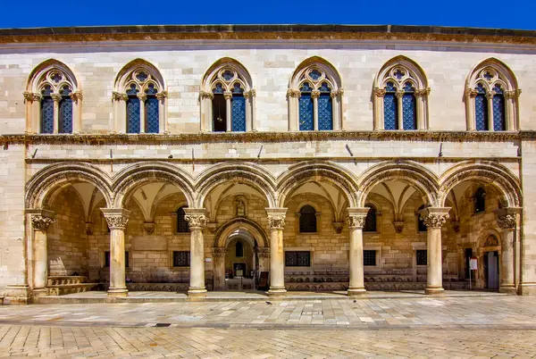 Hırvatistan 'ın Dubrovnik kentindeki Rektörler Sarayı' nın ön manzarası. Kemerli sütunlar, taş sütunlar ve açık mavi gökyüzü altında Gotik-Rönesans mimarisi. 