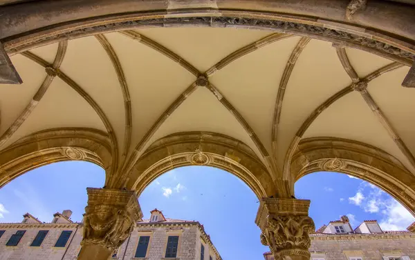 Hırvatistan 'ın Dubrovnik kentindeki Rektörler Sarayı' nın ön manzarası. Kemerli sütunlar, taş sütunlar ve açık mavi gökyüzü altında Gotik-Rönesans mimarisi. 