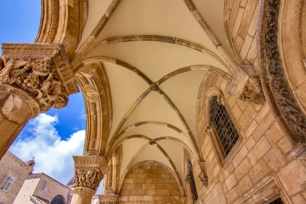 Hırvatistan 'ın Dubrovnik kentindeki Rektörler Sarayı' nın ön manzarası. Kemerli sütunlar, taş sütunlar ve açık mavi gökyüzü altında Gotik-Rönesans mimarisi. 