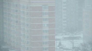Bir apartmanın arka planında dönen büyük kar taneleri..