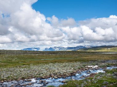 Nehirdeki mavi yansıma ve Norveç 'teki harnesvidda üzerindeki kayalar ve arka planda karla kaplı dağlar
