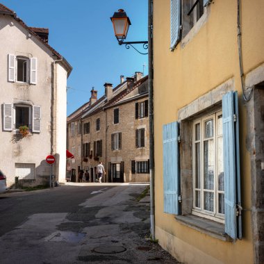 Orgelet, Fransa, 10 Ağustos 2023: Güneşli caddedeki insanlar ve Jura 'daki Fransız kasabası Orgelet' teki eski evler