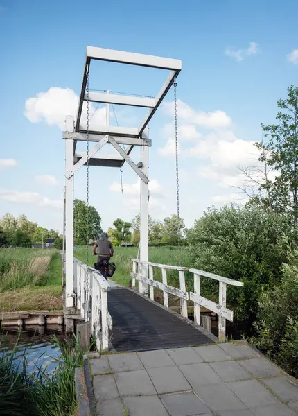 stock image man on bicycle passes drawbridge over smal canal in national park weerribben wieden near giethoorn in overijssel