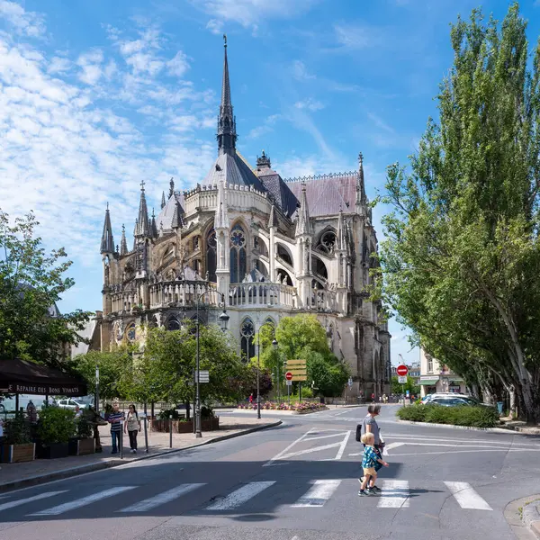 stock image reims, france, 18 july 2024: people cross the street in centre of french city reims behind famous cathedral