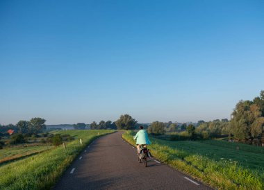 Kadın, sabahın erken saatlerinde Hollanda 'daki Nijmegen yakınlarındaki Oujpolder' de bisiklet sürüyor.