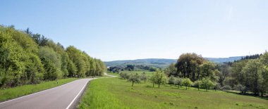 Alman doğa parkındaki ağaçların ve tarlaların taze bahar renkleriyle dolu kırsal alan mavi gökyüzünün altında saar-hunsrueck